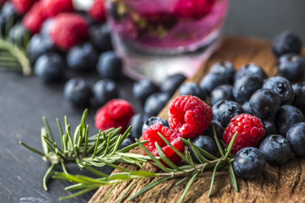 fruits rouges frais de la-mauvaise-graine-pepiniere-bio à Beaumont-sur-lèze sur planche avec romarin,